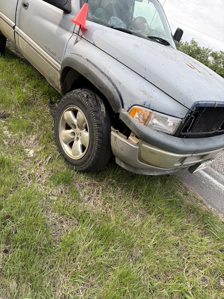 Pickup stopped on a grass shoulder with a flat front tire